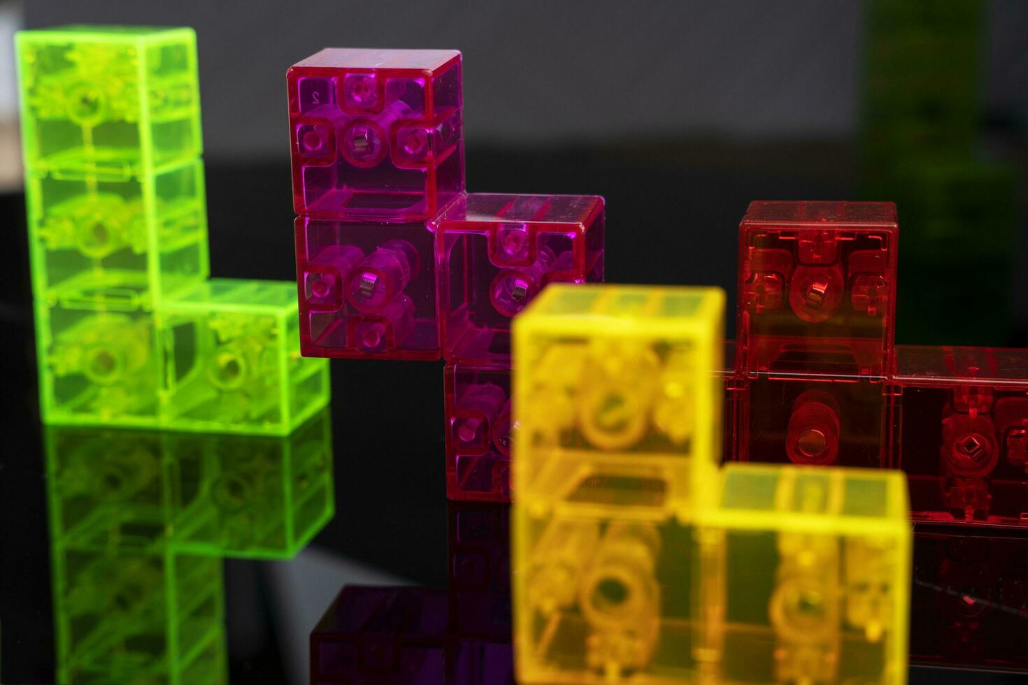 three-dimensional tetris. scattered colored tetris figures on glossy black glass photo