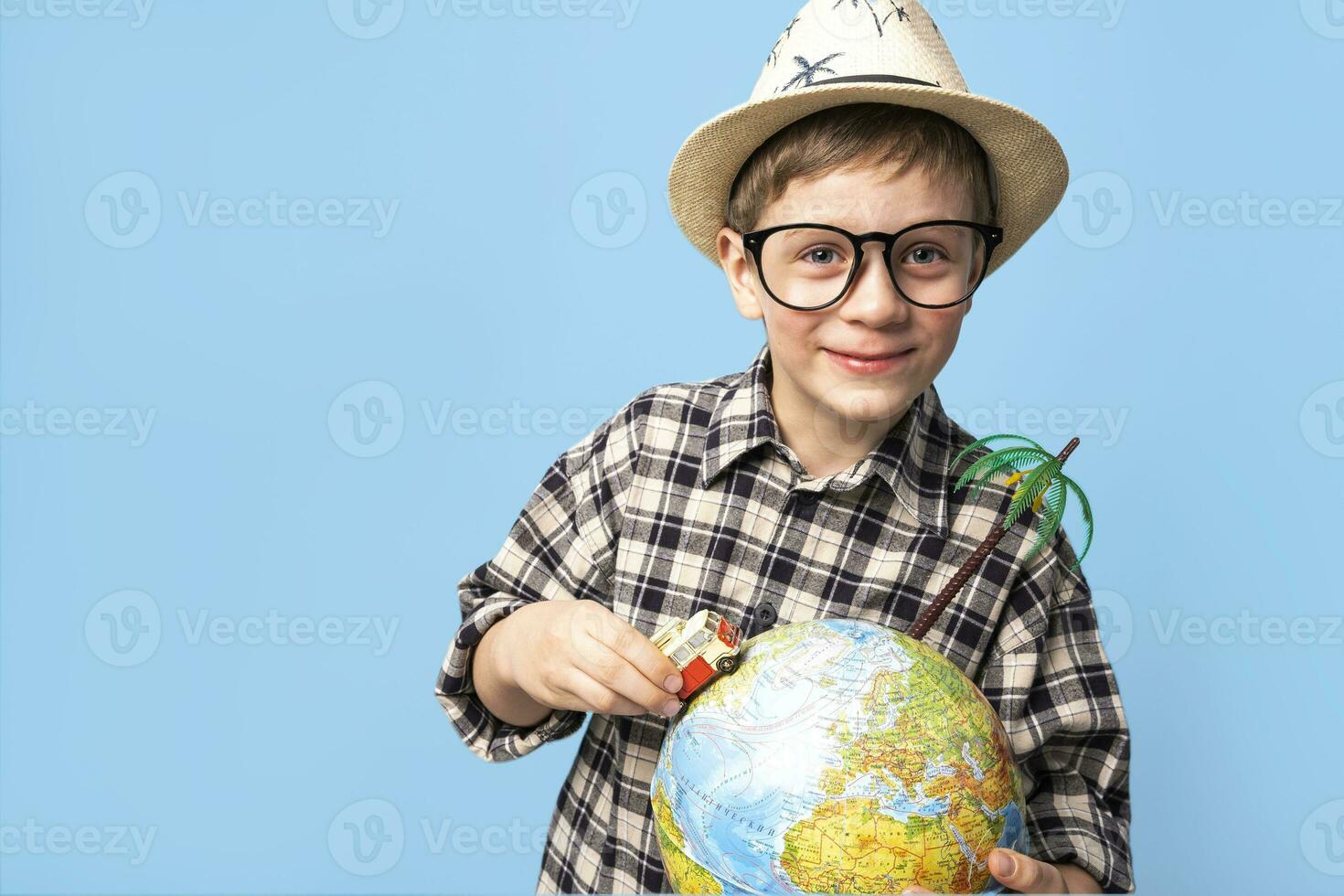 happy boy in a hat from the sun rides around the globe in a toy car photo