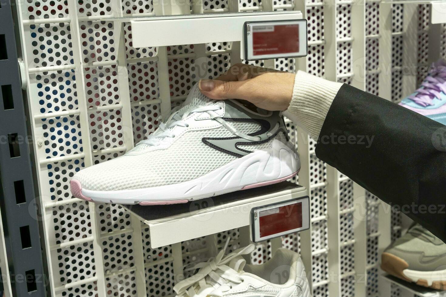 women's hands hold a new sneaker taken from the shelf of sports store photo