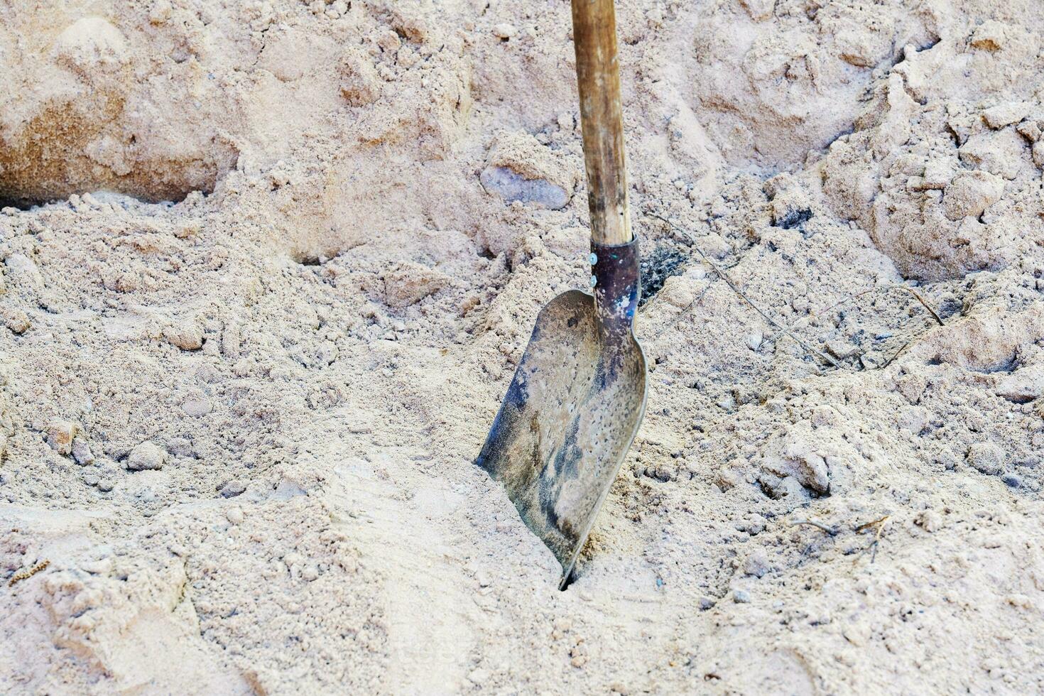 a pile of yellow river sand with a shovel on a construction site photo