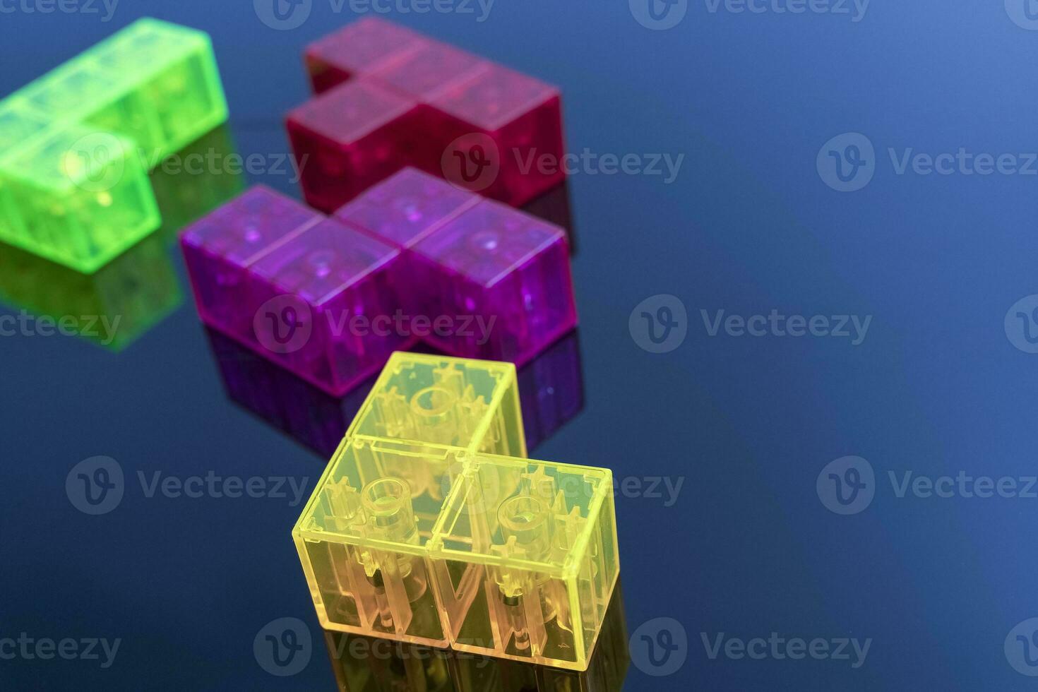 three-dimensional colored tetris figures on glossy black glass, space for copying photo