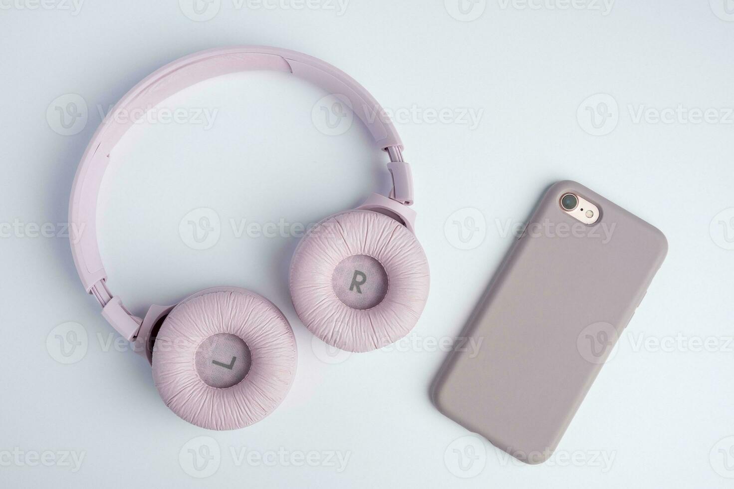 rosado inalámbrico auriculares y un teléfono inteligente en un blanco antecedentes. música hora foto