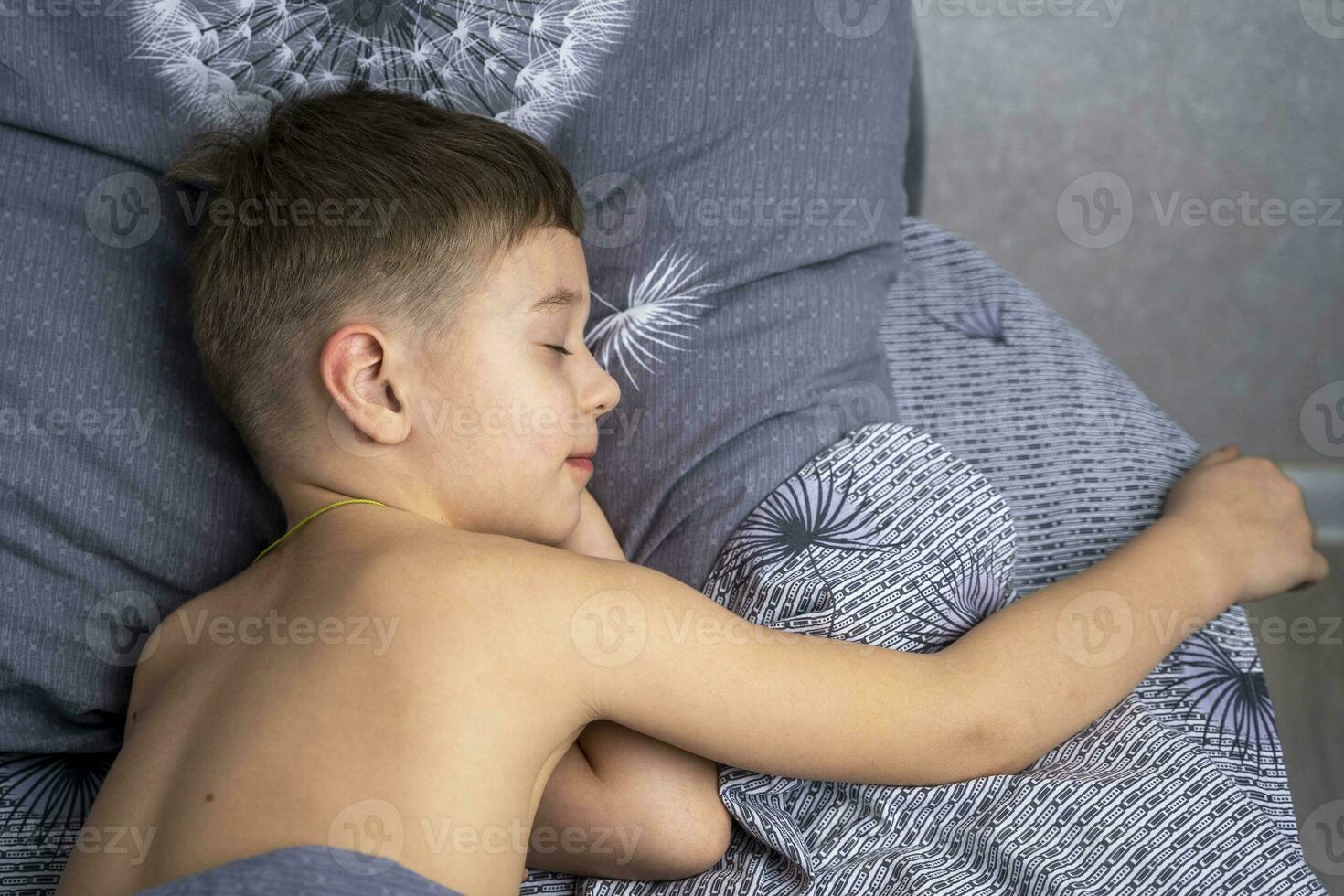 un linda caucásico chico de 5 5 años antiguo es dormido en cama. descansar, hogar comodidad foto