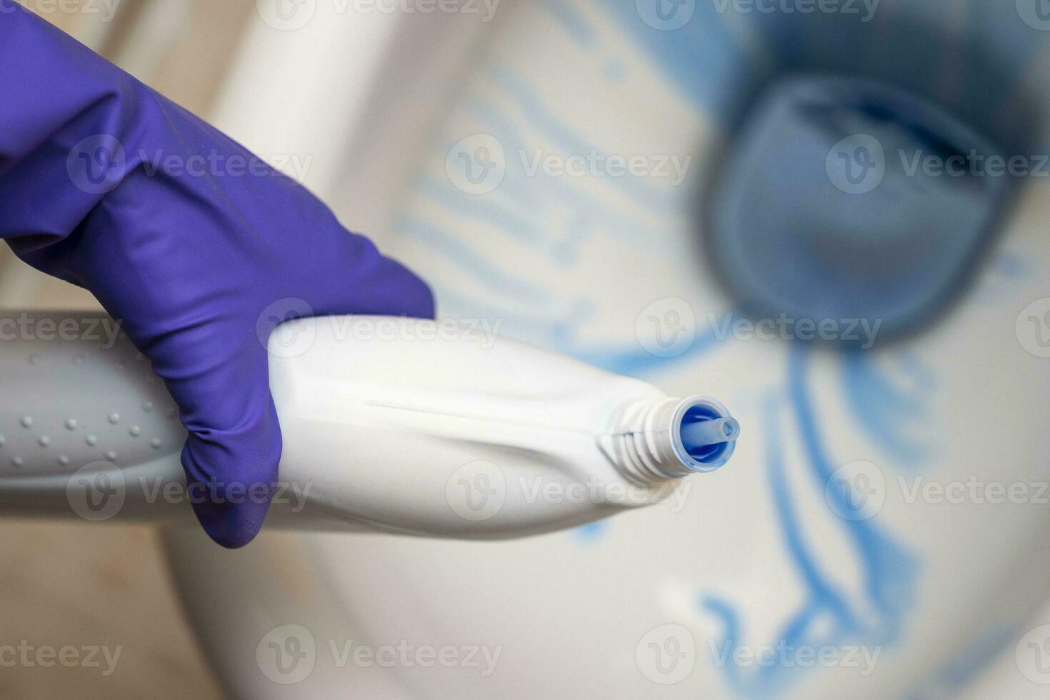 las manos del limpiador lavan el inodoro en el baño con detergente y guantes de goma foto