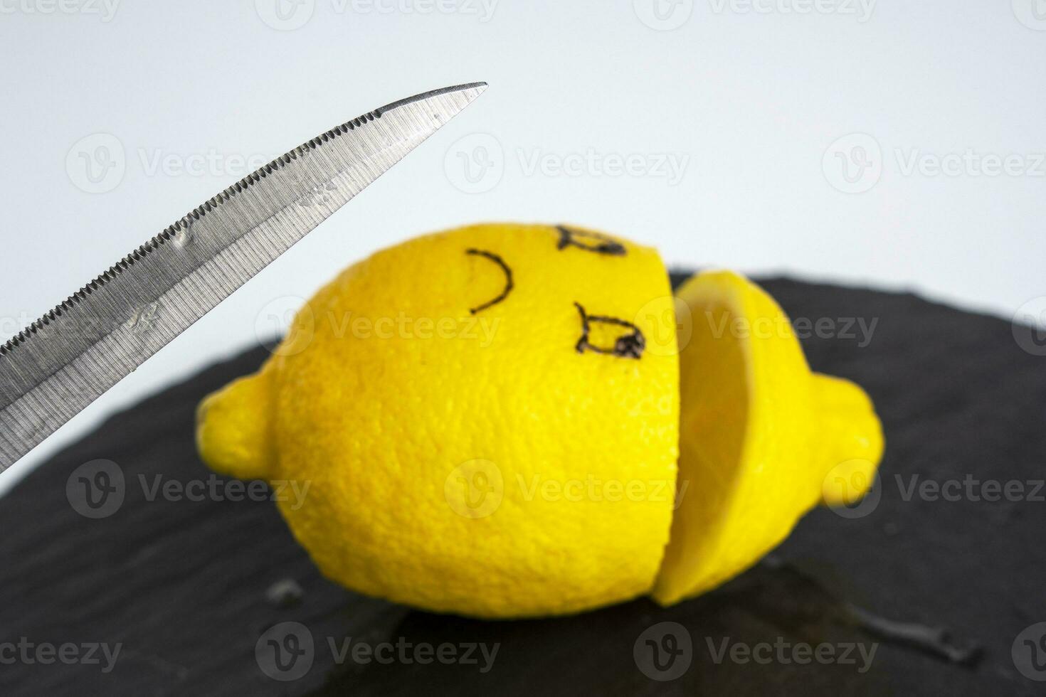 a kitchen knife and a lemon with painted eyes cut in half lies on a cutting board photo