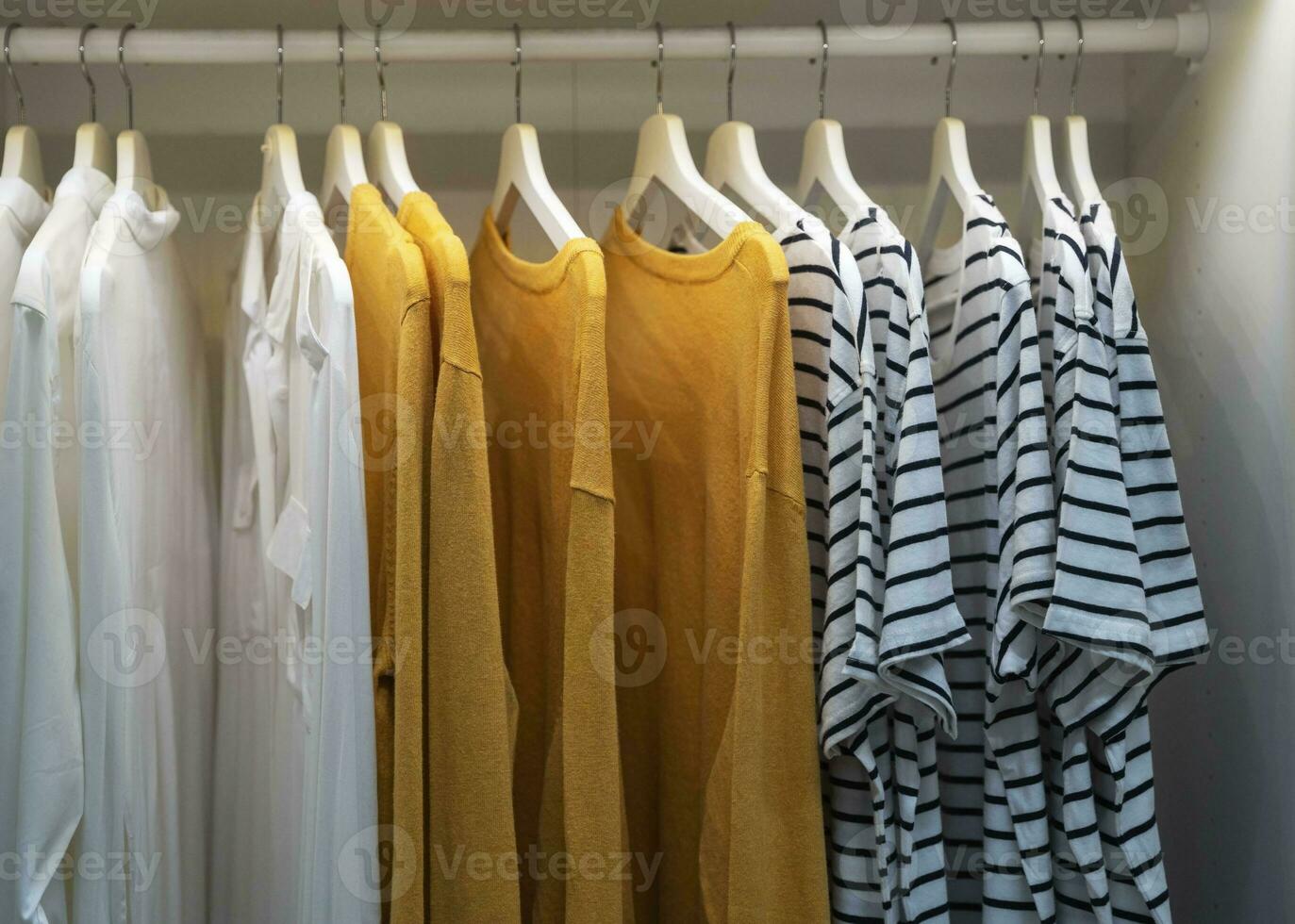 clothes, t-shirts, dresses hang on a hanger in the home closet photo