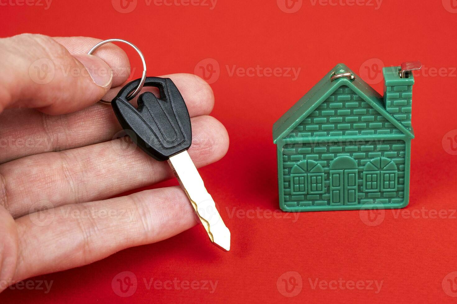 man's hand holding the key to the house, and a model of the house photo