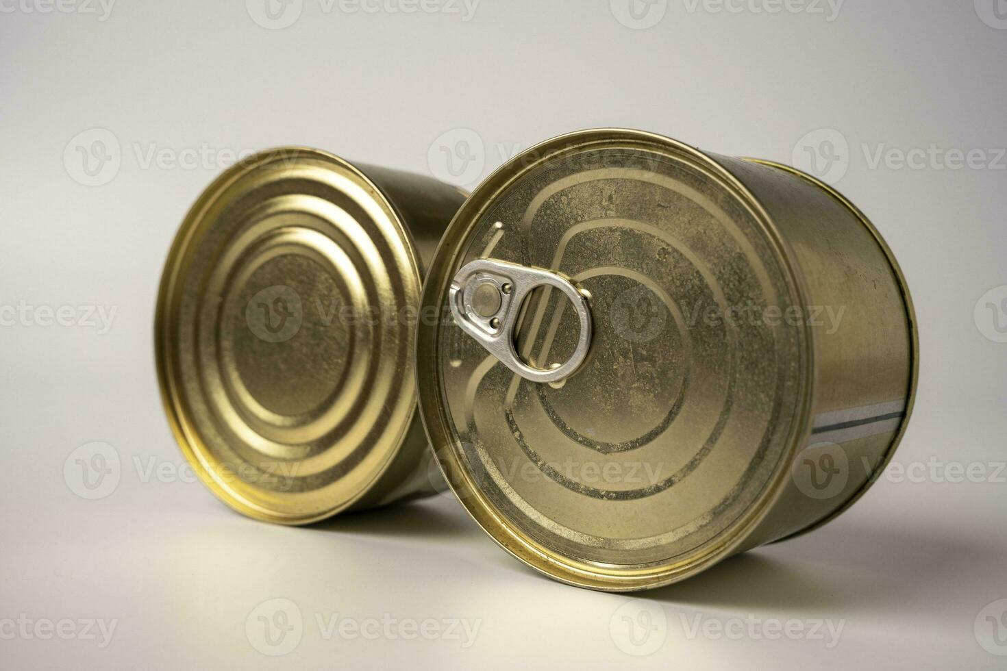 Two round shiny tin cans with canned food are lying on the table on a white background photo