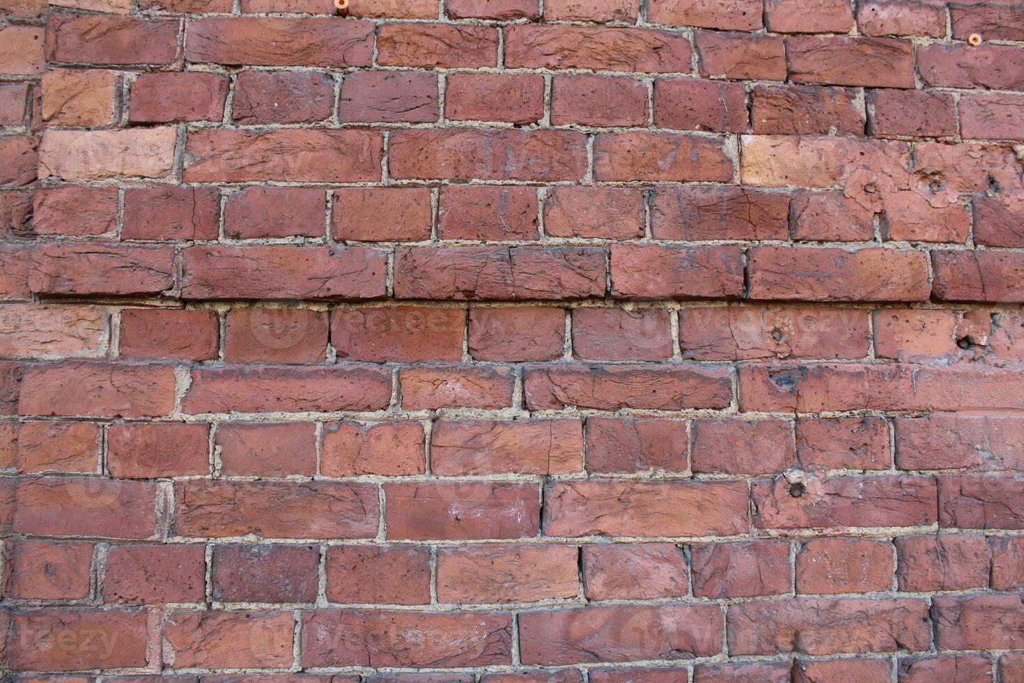 Red brick pattern. Old brick wall with cracks and scratches. Horizontal wide brickwall background. Distressed wall with broken bricks texture. Vintage house facade. photo