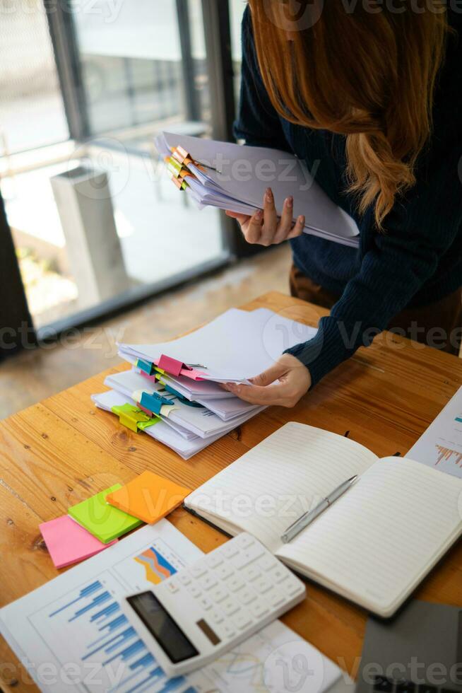Businesswoman hands working on stacks of paper documents to search and review documents piled on table before sending them to board of directors to use  correct documents in meeting with Businessman photo