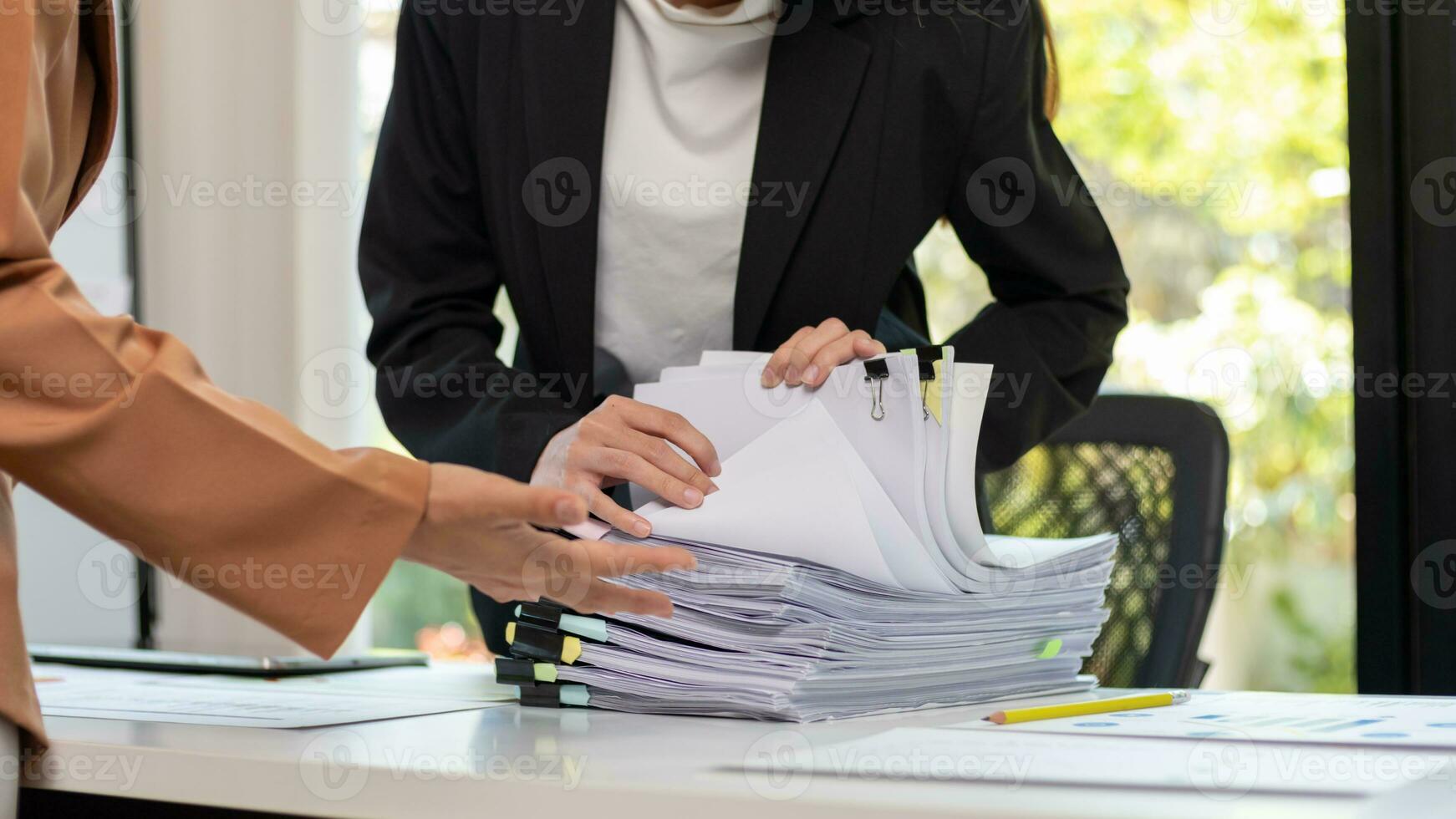 mujer de negocios manos trabajando en pilas de papel documentos a buscar y revisión documentos apilado en mesa antes de enviando ellos a tablero de directores a utilizar correcto documentos en reunión con empresario foto