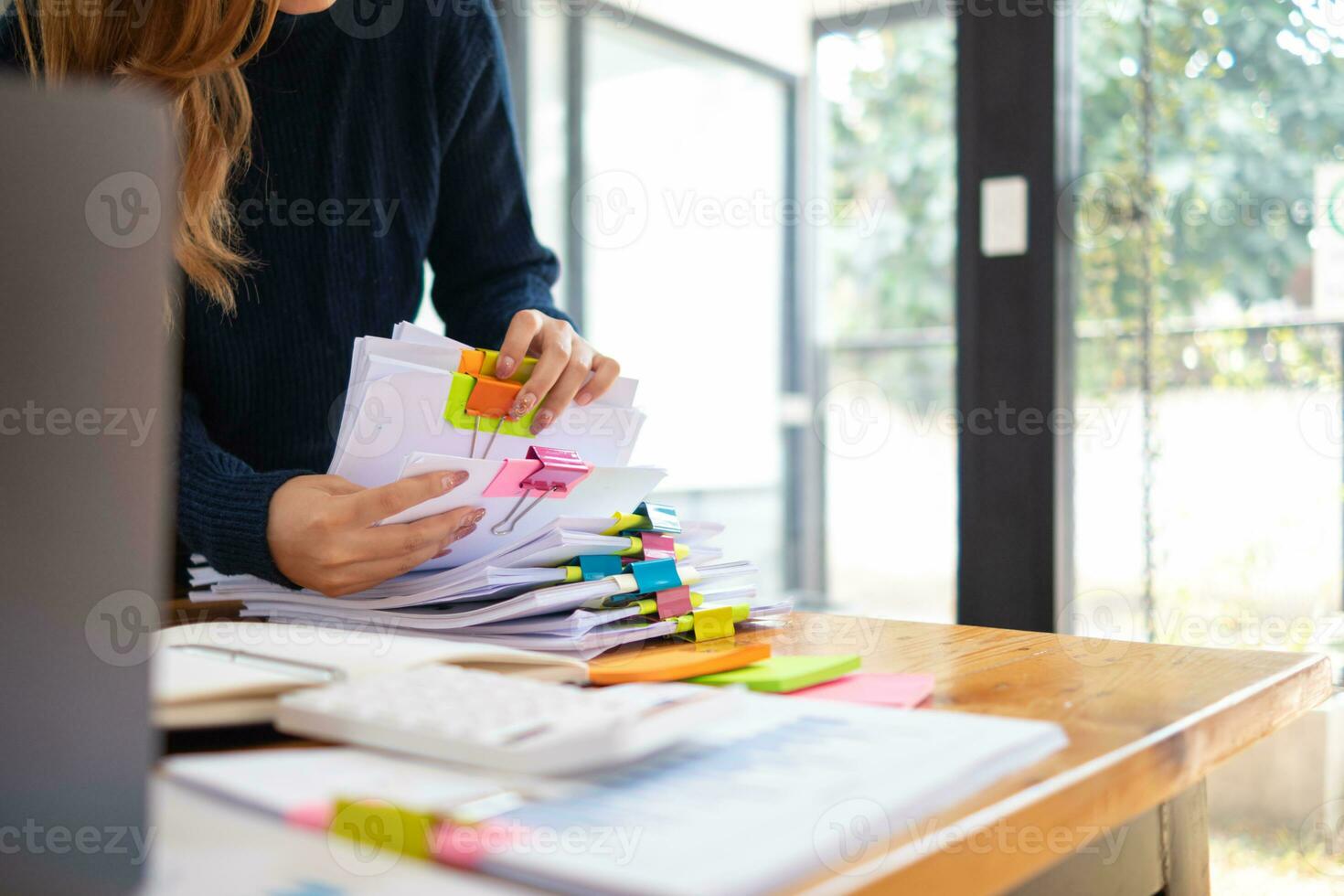 Businesswoman hands working on stacks of paper documents to search and review documents piled on table before sending them to board of directors to use  correct documents in meeting with Businessman photo