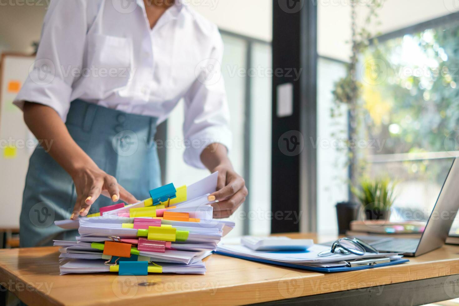 Businesswoman hands working on stacks of paper documents to search and review documents piled on table before sending them to board of directors to use  correct documents in meeting with Businessman photo