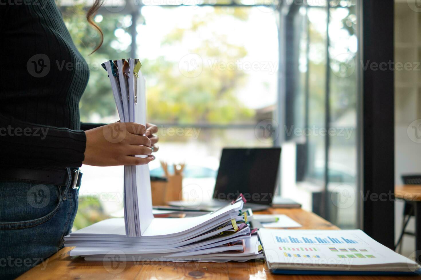 mujer de negocios manos trabajando en pilas de papel documentos a buscar y revisión documentos apilado en mesa antes de enviando ellos a tablero de directores a utilizar correcto documentos en reunión con empresario foto