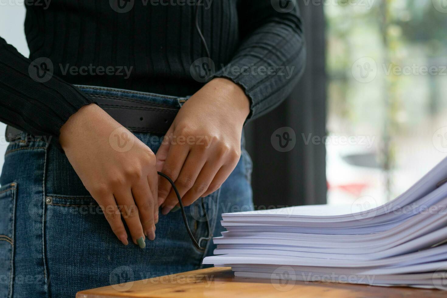 mujer de negocios manos trabajando en pilas de papel documentos a buscar y revisión documentos apilado en mesa antes de enviando ellos a tablero de directores a utilizar correcto documentos en reunión con empresario foto