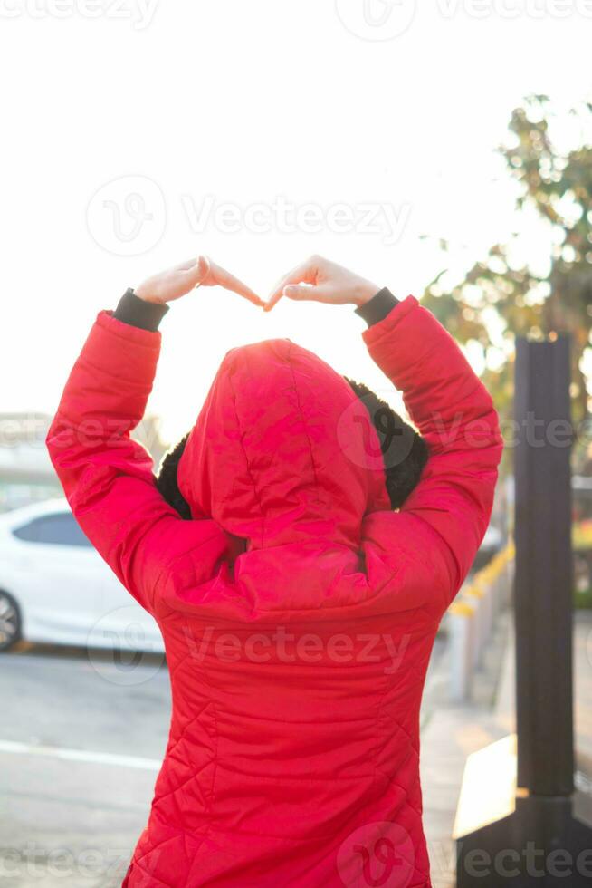 woman holds her hand above her head to form heart symbol that represents love, friendship and kindness between lovers and friends. heart symbol is concept that represents friendship, love and kindness photo