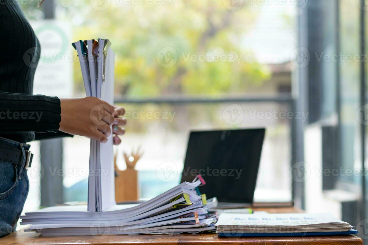 mujer de negocios manos trabajando en pilas de papel documentos a buscar y revisión documentos apilado en mesa antes de enviando ellos a tablero de directores a utilizar correcto documentos en reunión con empresario foto