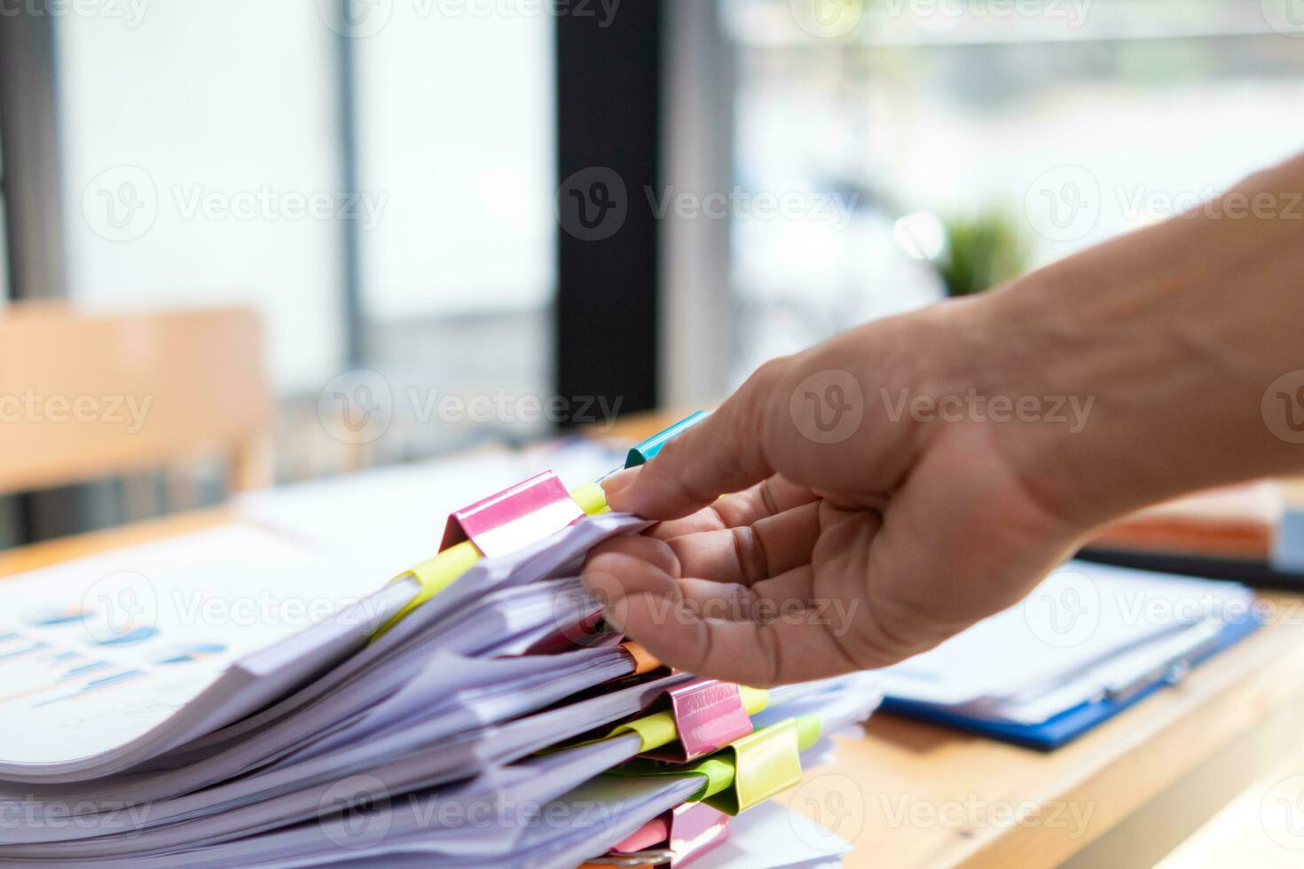 mujer de negocios manos trabajando en pilas de papel documentos a buscar y revisión documentos apilado en mesa antes de enviando ellos a tablero de directores a utilizar correcto documentos en reunión con empresario foto