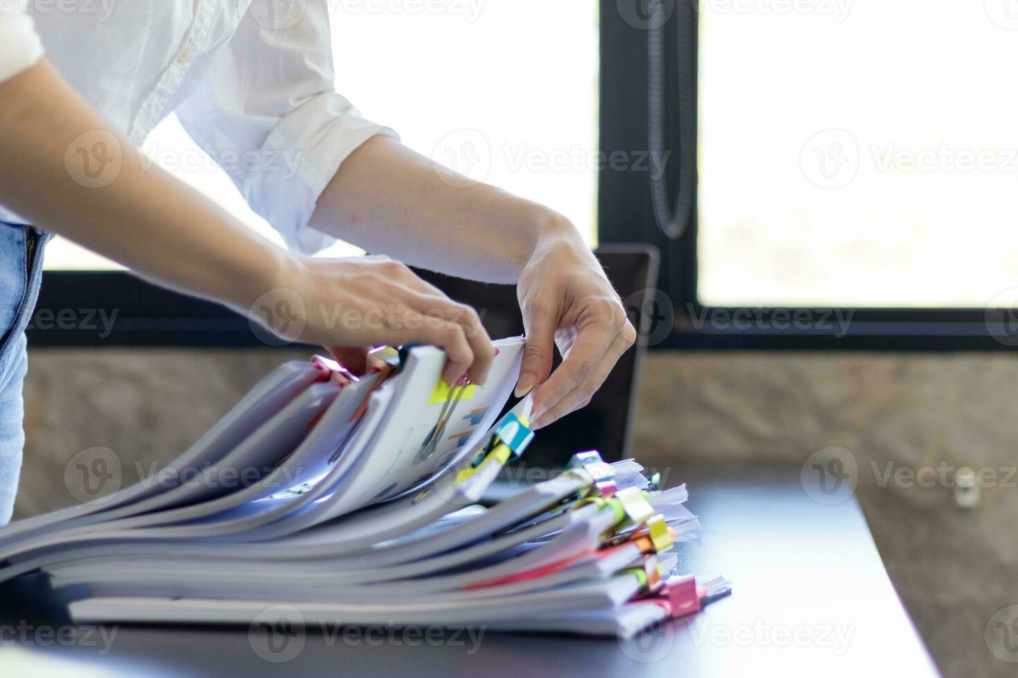 Businesswoman hands working on stacks of paper documents to search and review documents piled on table before sending them to board of directors to use  correct documents in meeting with Businessman photo