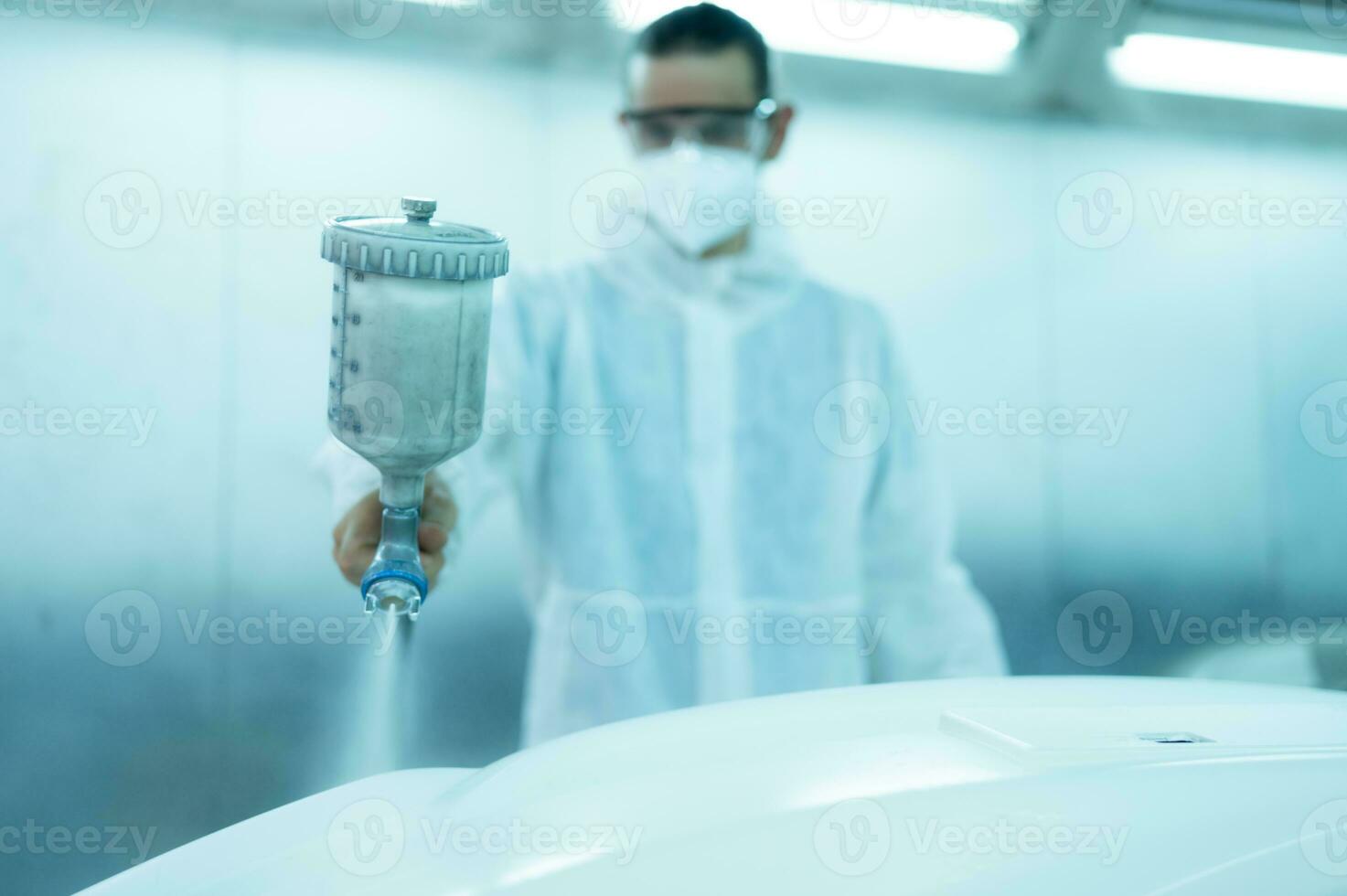 Auto mechanic in car spray room giving the spray nozzle injected into the car front bumper of the car with refinement in order to create beauty that blends with the original color of the car photo