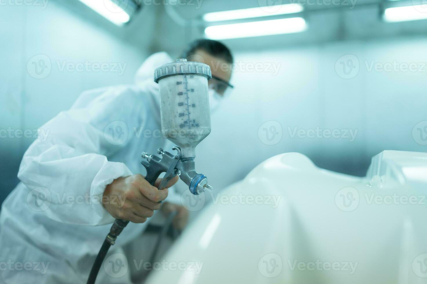 Auto mechanic in car spray room giving the spray nozzle injected into the car front bumper of the car with refinement in order to create beauty that blends with the original color of the car photo