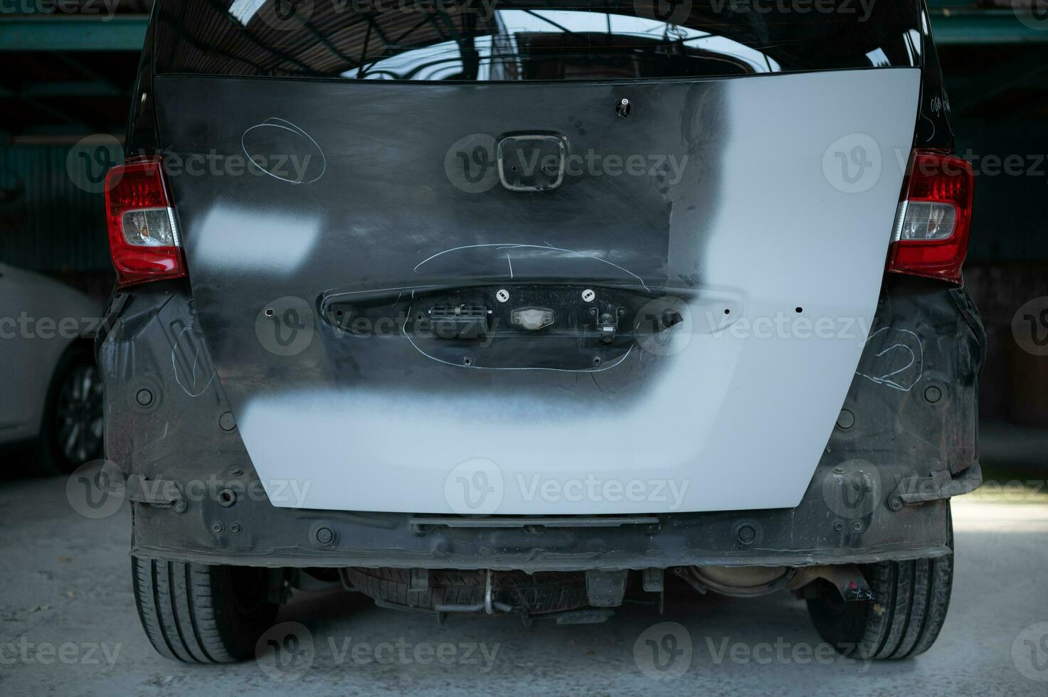 A car mechanic checks the condition of a car body to be repaired after a collision. by marking the X that need to be repaired photo