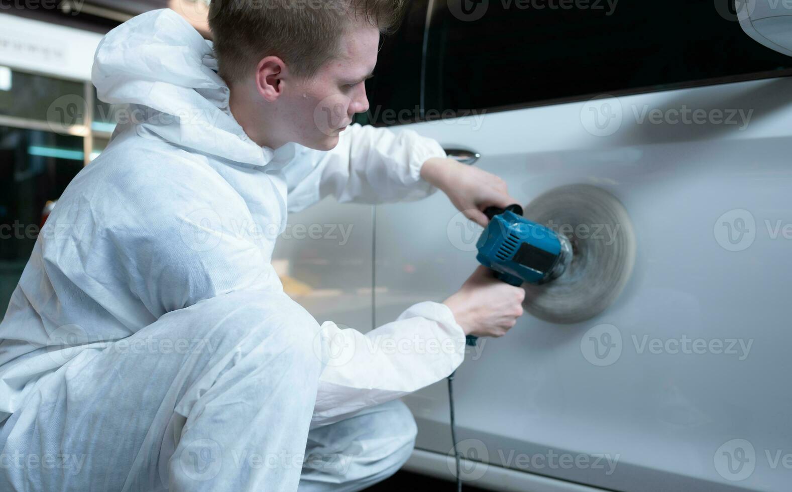 Auto mechanic use an electric polisher to polish the dried car paint. After passing the paint from the car painting room photo