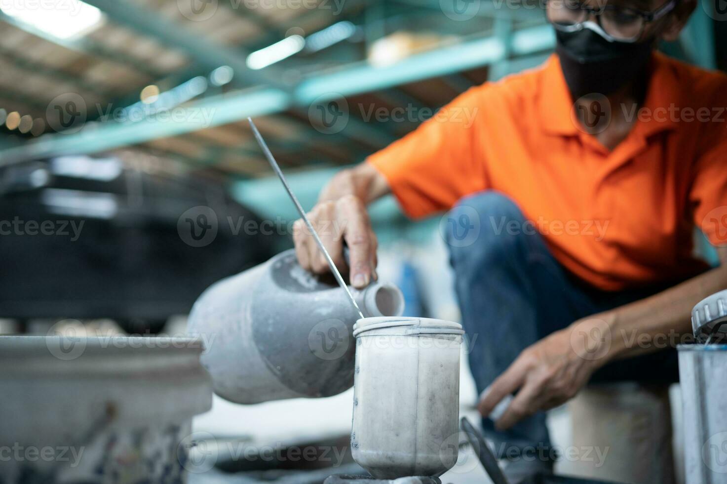 Auto mechanic in spray painting room mixing paint for use in spray painting a car that has undergone body repair photo