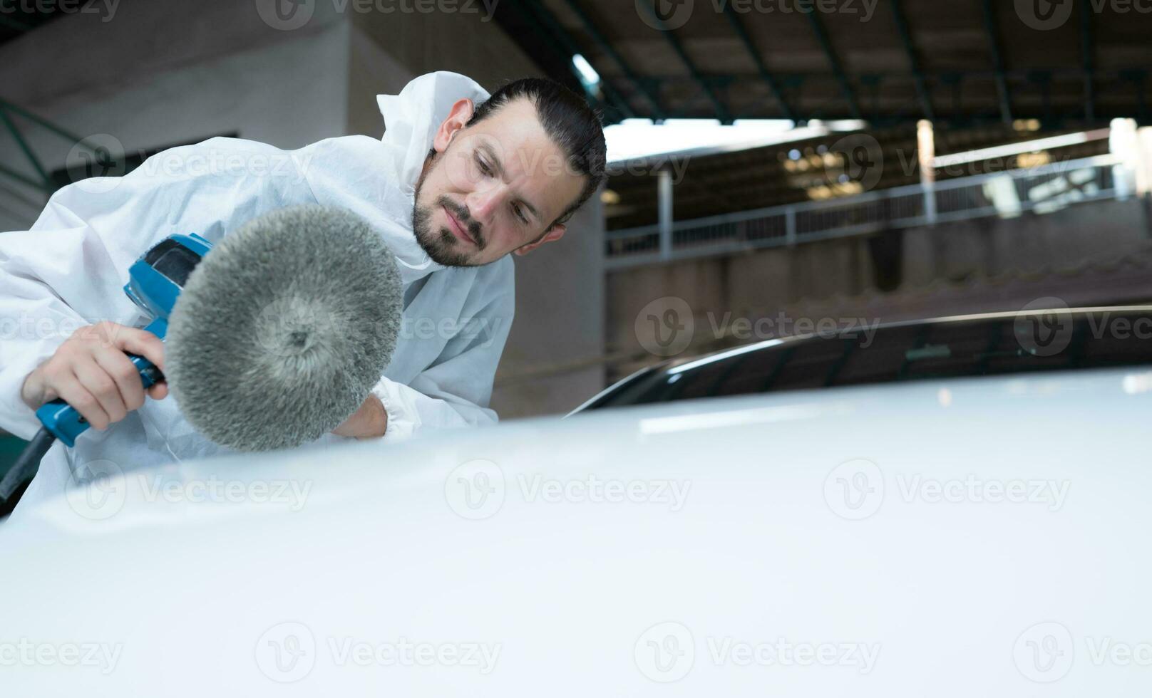 Auto mechanic use an electric polisher to polish the dried car paint. After passing the paint from the car painting room photo