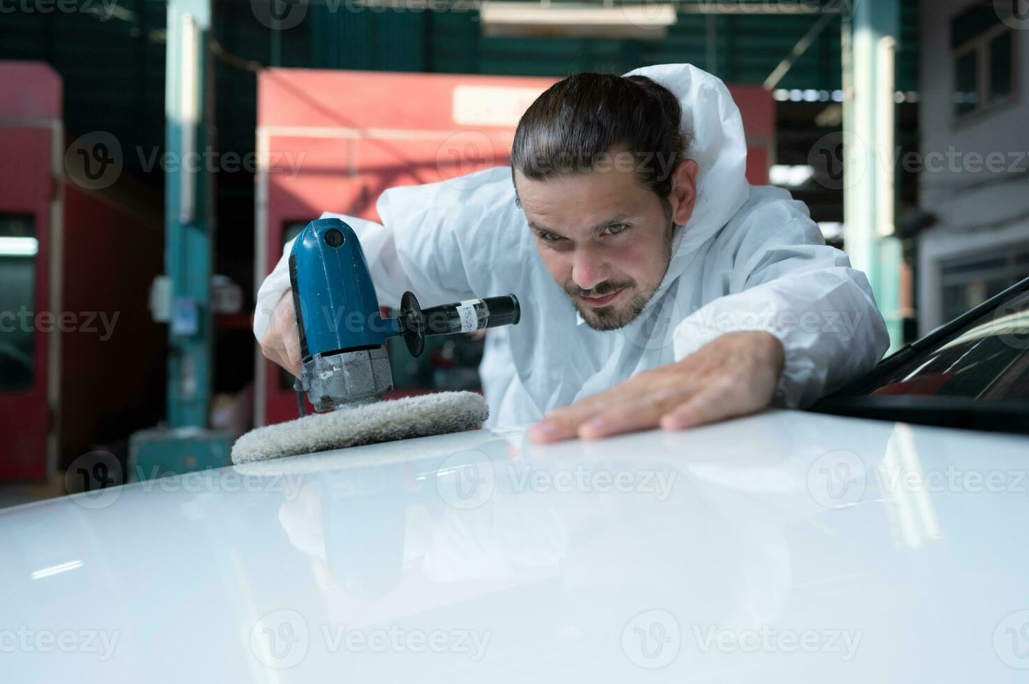 Auto mechanic use an electric polisher to polish the dried car paint. After passing the paint from the car painting room photo