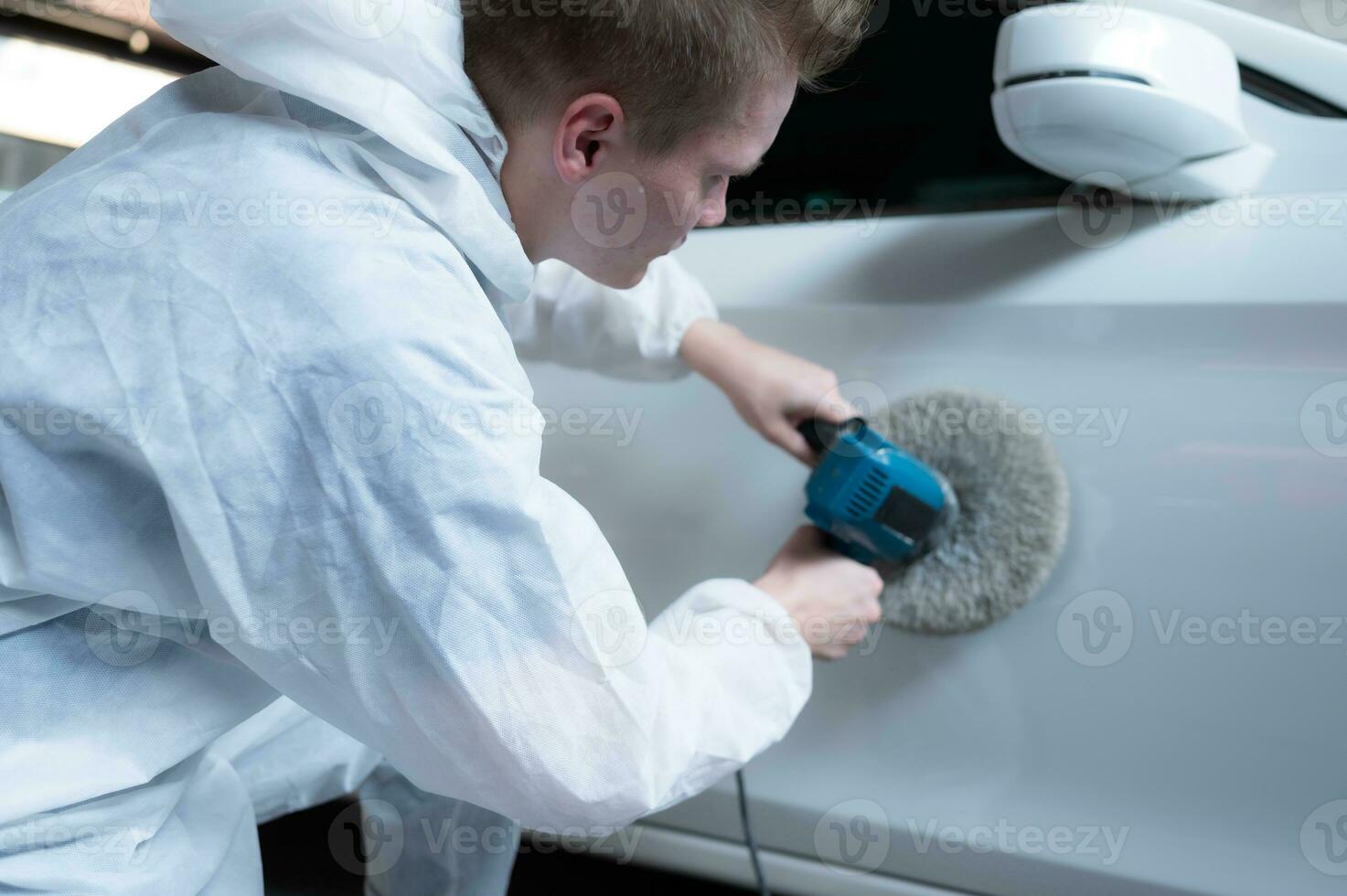 Auto mechanic use an electric polisher to polish the dried car paint. After passing the paint from the car painting room photo
