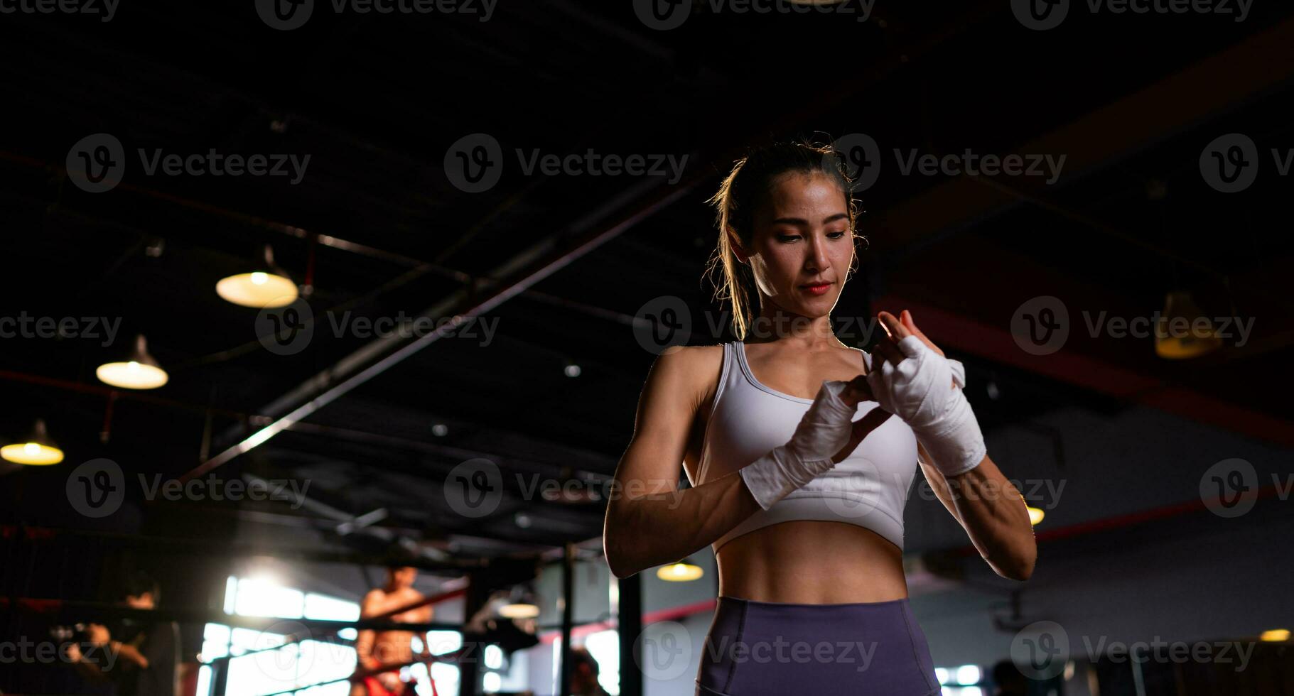 retrato de mujer aprendizaje muay tailandés a construir arriba el fuerza de el cuerpo y utilizar eso para autodefensa. son utilizando mano envuelve antes de poniendo en boxeo guantes para boxeo foto