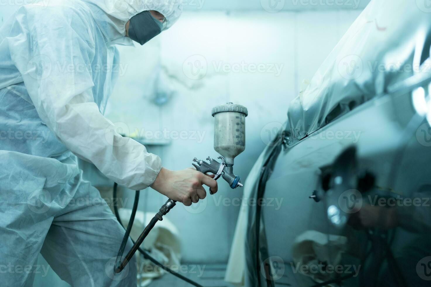 Auto mechanic in car spray room Use a spray nozzle Injected to the side of the car body with care to create beauty that blends with the original color of the car. photo