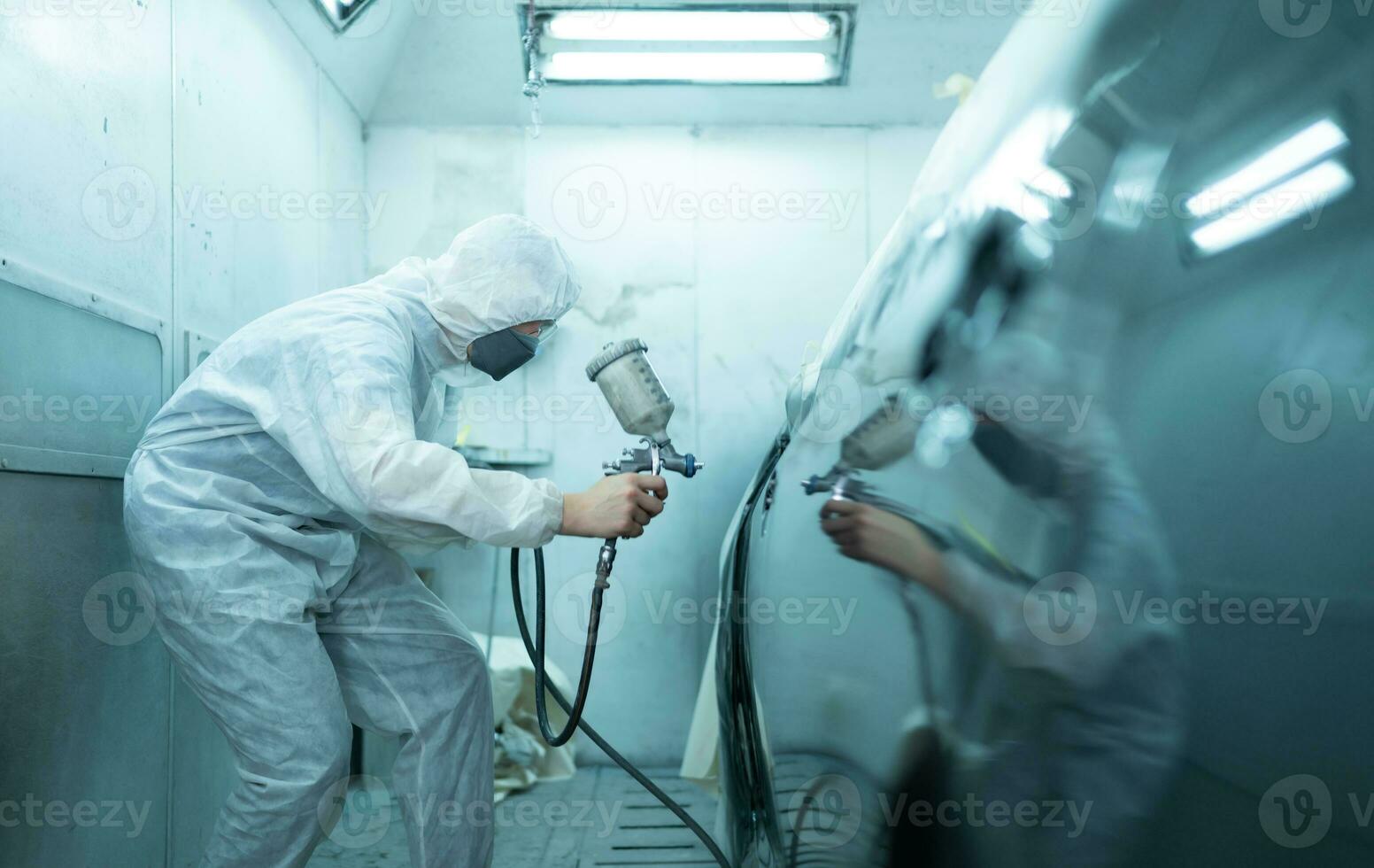 Auto mechanic in car spray room Use a spray nozzle Injected to the side of the car body with care to create beauty that blends with the original color of the car. photo