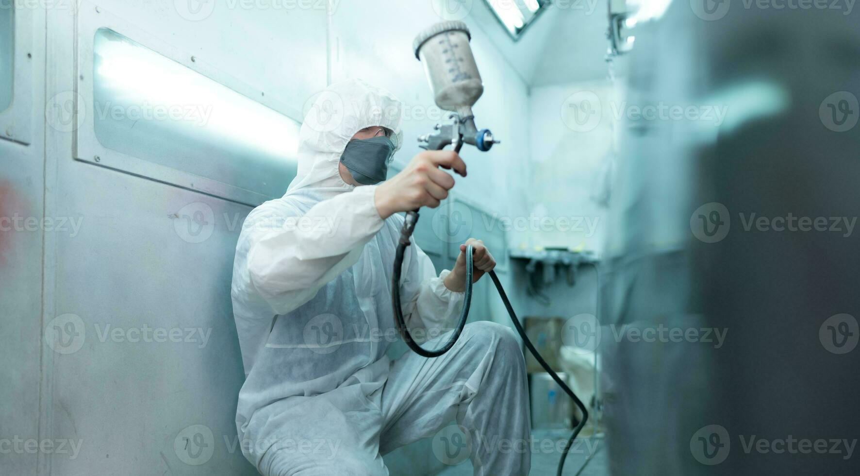 Auto mechanic in car spray room Use a spray nozzle Injected to the side of the car body with care to create beauty that blends with the original color of the car. photo