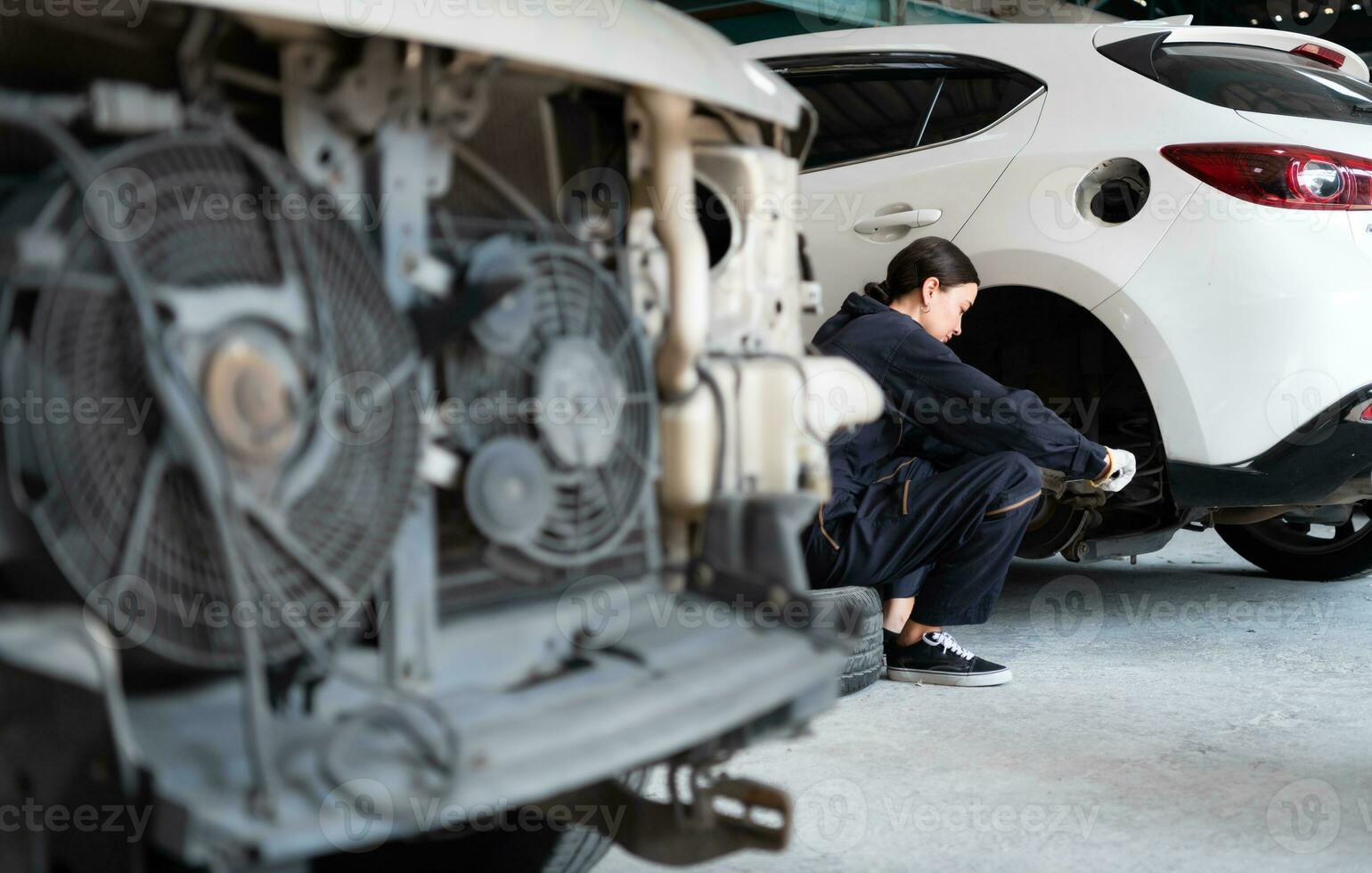 A female mechanic checking the condition of a car's brake discs and the condition of the tires that have been used for a while photo