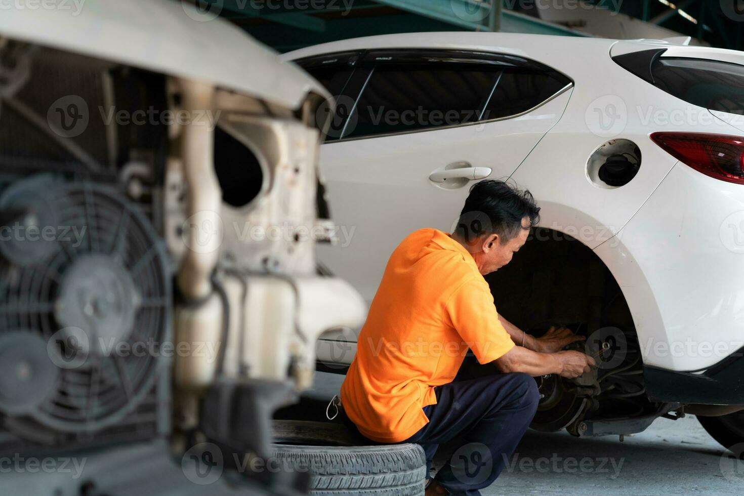 A auto mechanic checking the condition of a car's brake discs and the condition of the tires that have been used for a while photo