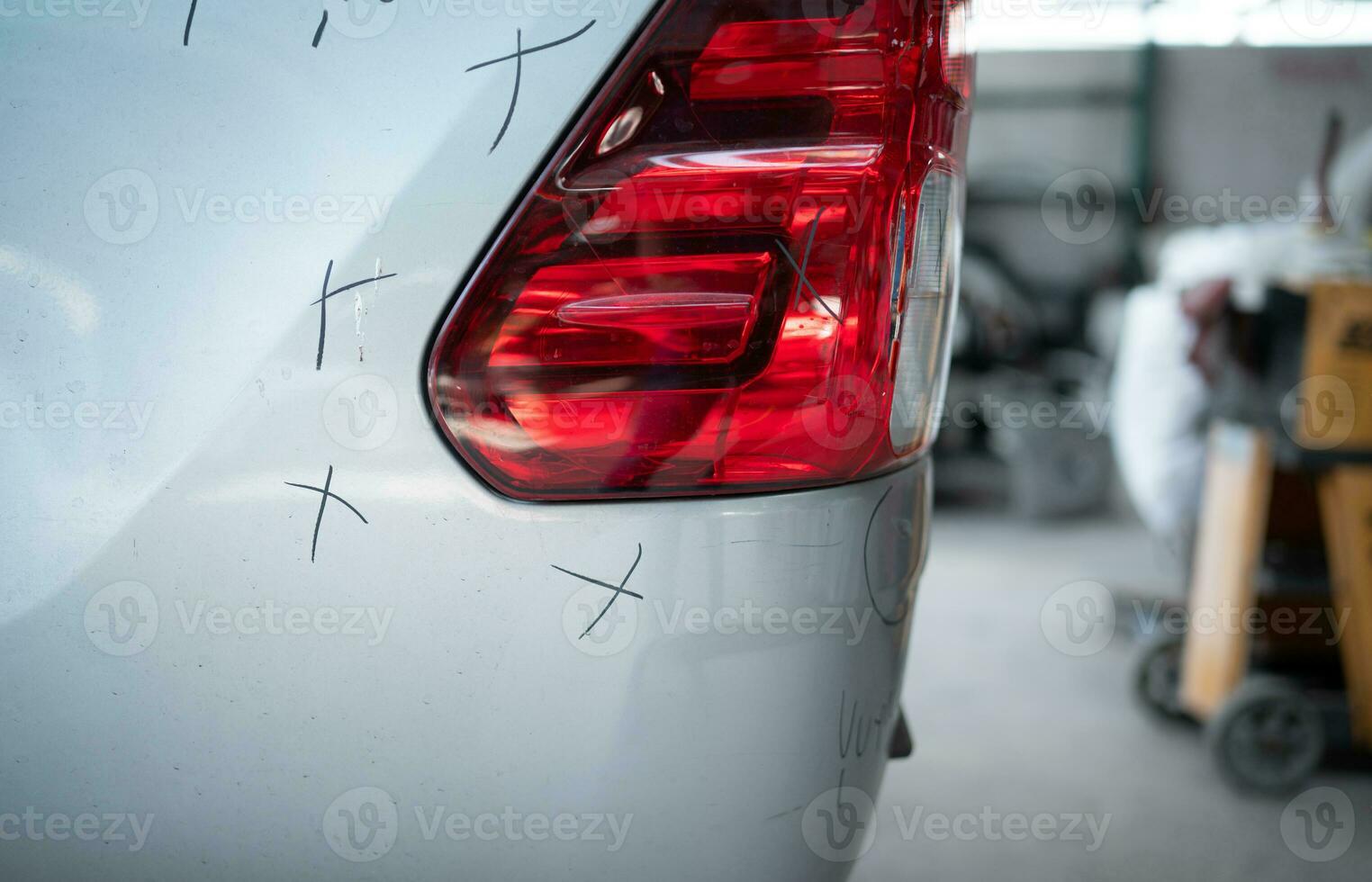 A car mechanic checks the condition of a car body to be repaired after a collision. by marking the X that need to be repaired photo
