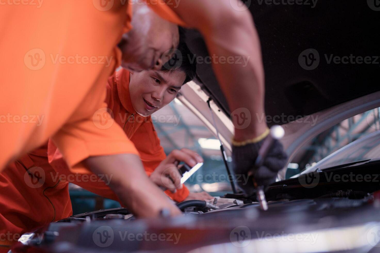 ambos de auto mecánica son inspeccionando el motor de un clientes coche siendo trajo en para reparar a un cochera. foto