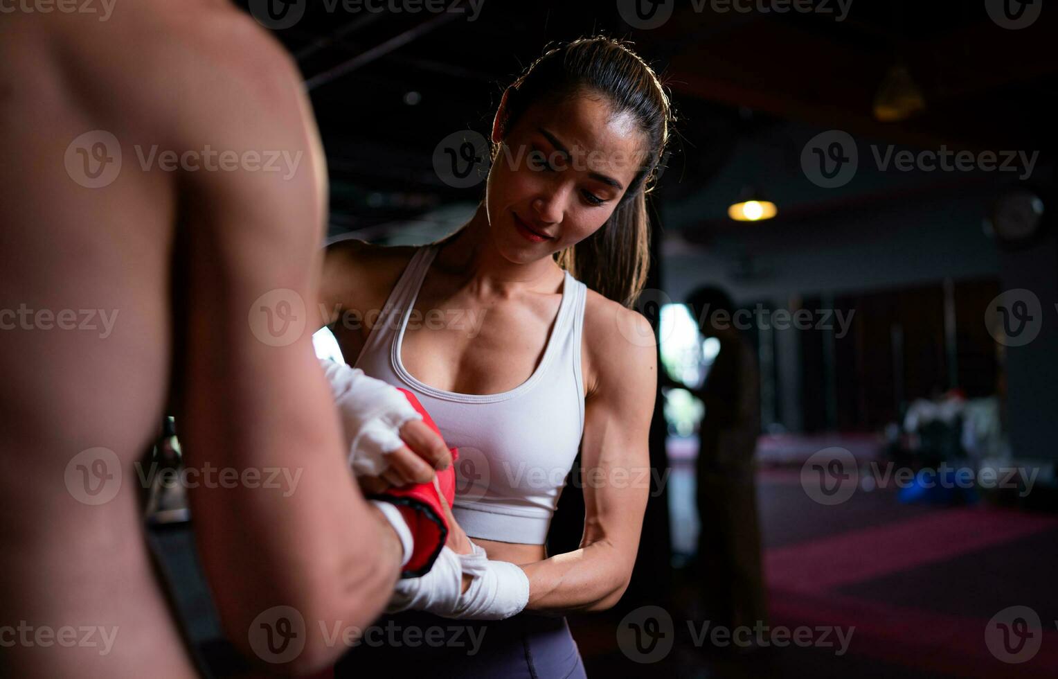 Foreign boxer with young Asian woman helping boxer with boxing bandage before putting on the boxing gloves and continuing to practice, Muay Thai, Thai martial arts. photo