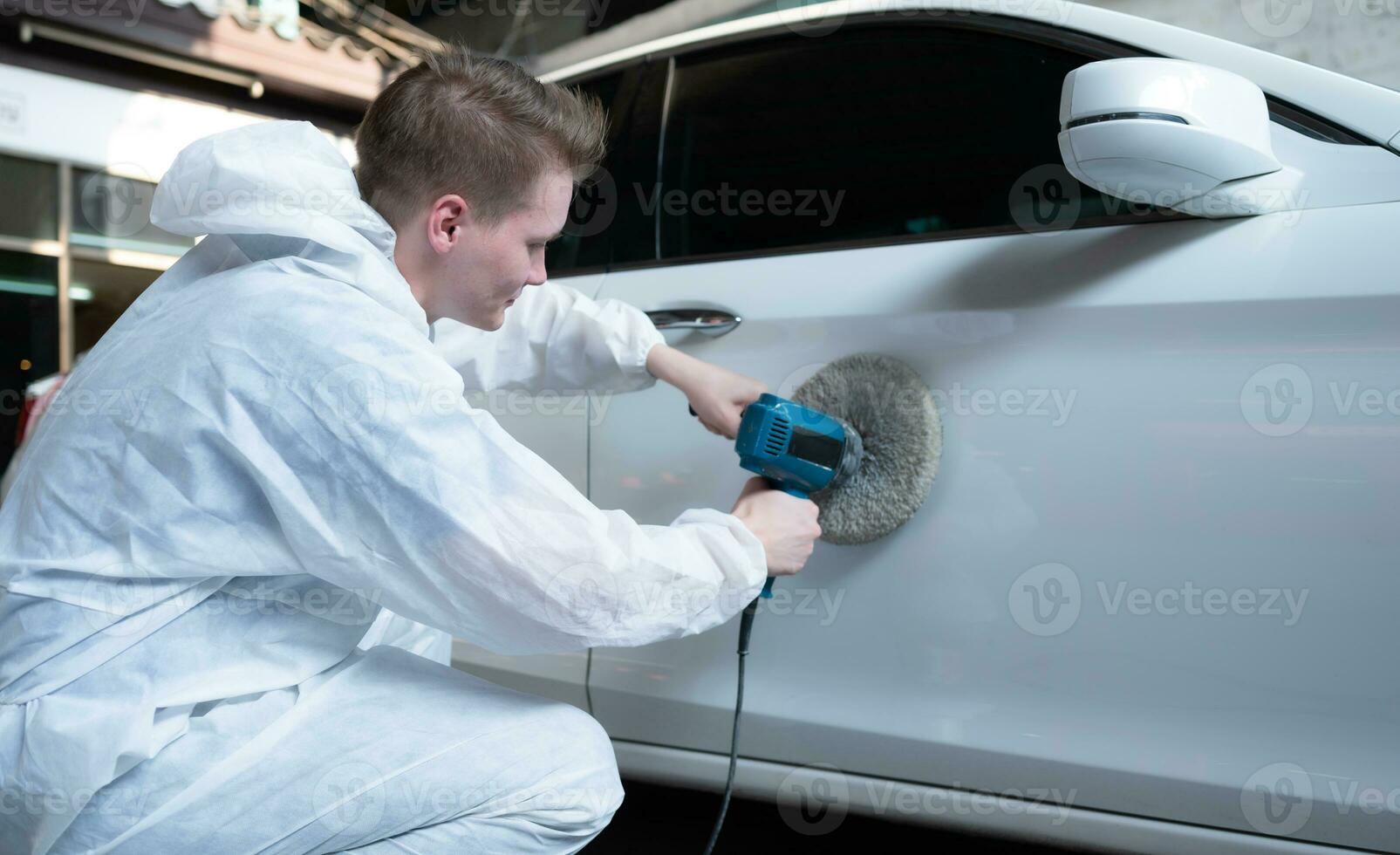 Auto mechanic use an electric polisher to polish the dried car paint. After passing the paint from the car painting room photo