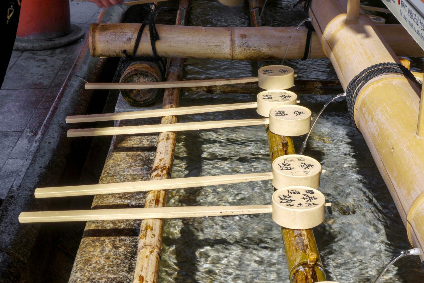 Japanese bamboo dippers for clean hands and mouths by clear water before enter to respect in Fushimi Inari Shrine. photo
