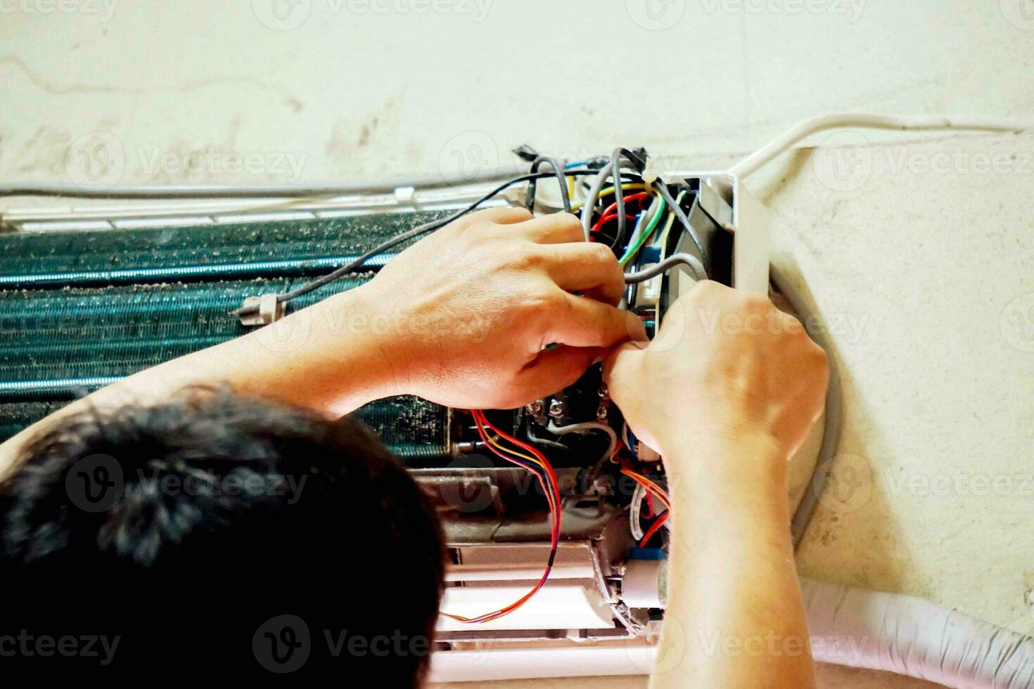 Closeup hands of electric repair technician fix an electronic board of home's air conditioner after washing in the bedroom. photo