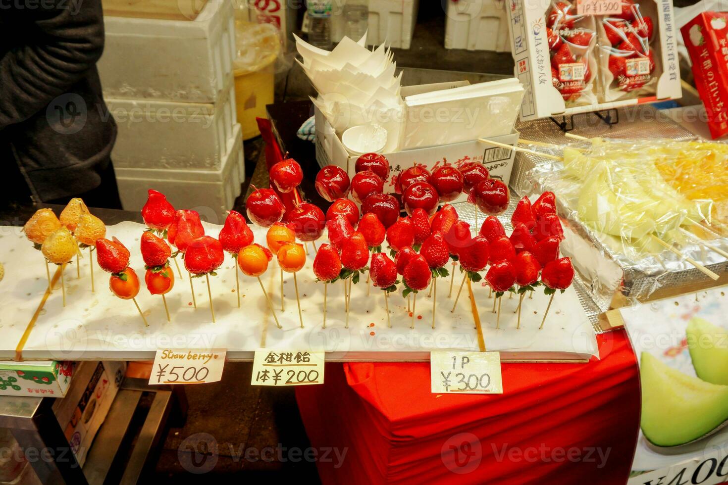 Strawberry and Cherry in wooden sticks  with Japanese name and price labels. Sale at Kuromon street market, Osaka, Japan. photo