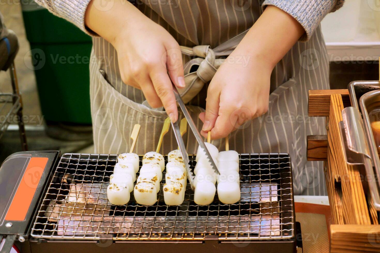 manos de cocinero utilizando un alicates tenazas japonés bocadillo en el parrilla a preparar para rebaja a clientes en el mercado. foto
