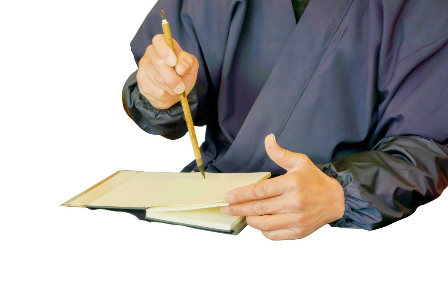 Japanese man wearing a blue national dress and his hand holding a Chinese brush acting write some thing on a note book isolate on white background and make with paths. photo