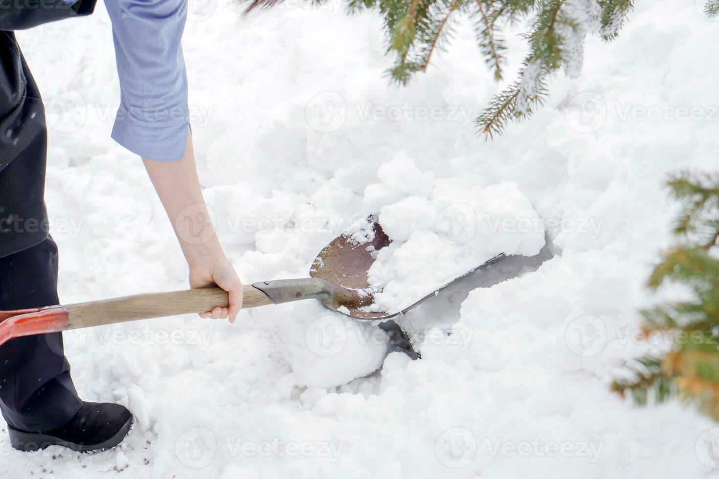 de cerca mano sostener y utilizando pala cucharón y despejado montón nieve en piso. foto