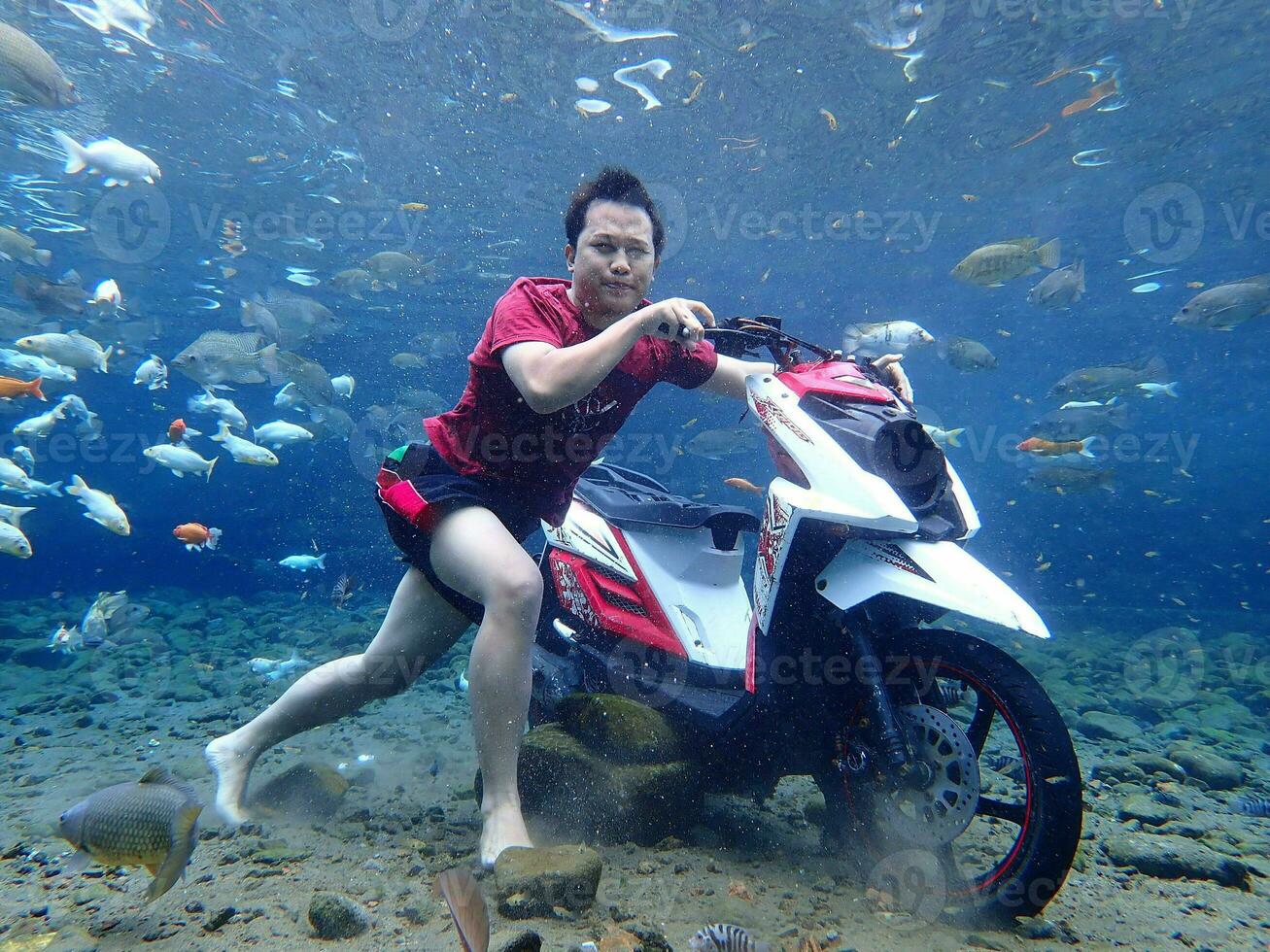 Klaten, Umbul ponggok, Indonesia, July 22, 2022,  a man taking a photo under clear water