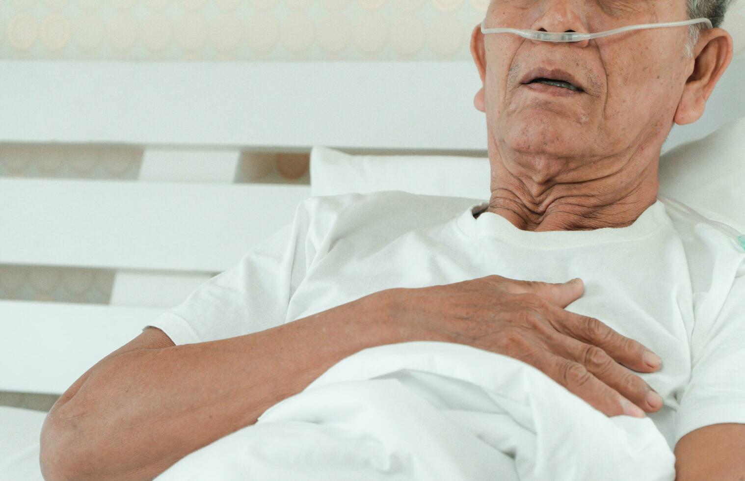 triste mayor hombre acostado en el hospital cama y con un nasal respiración tubo para tratamiento respiratorio. concepto de salud cuidado para el anciano, cuarentena coronavirus covid-19 foto