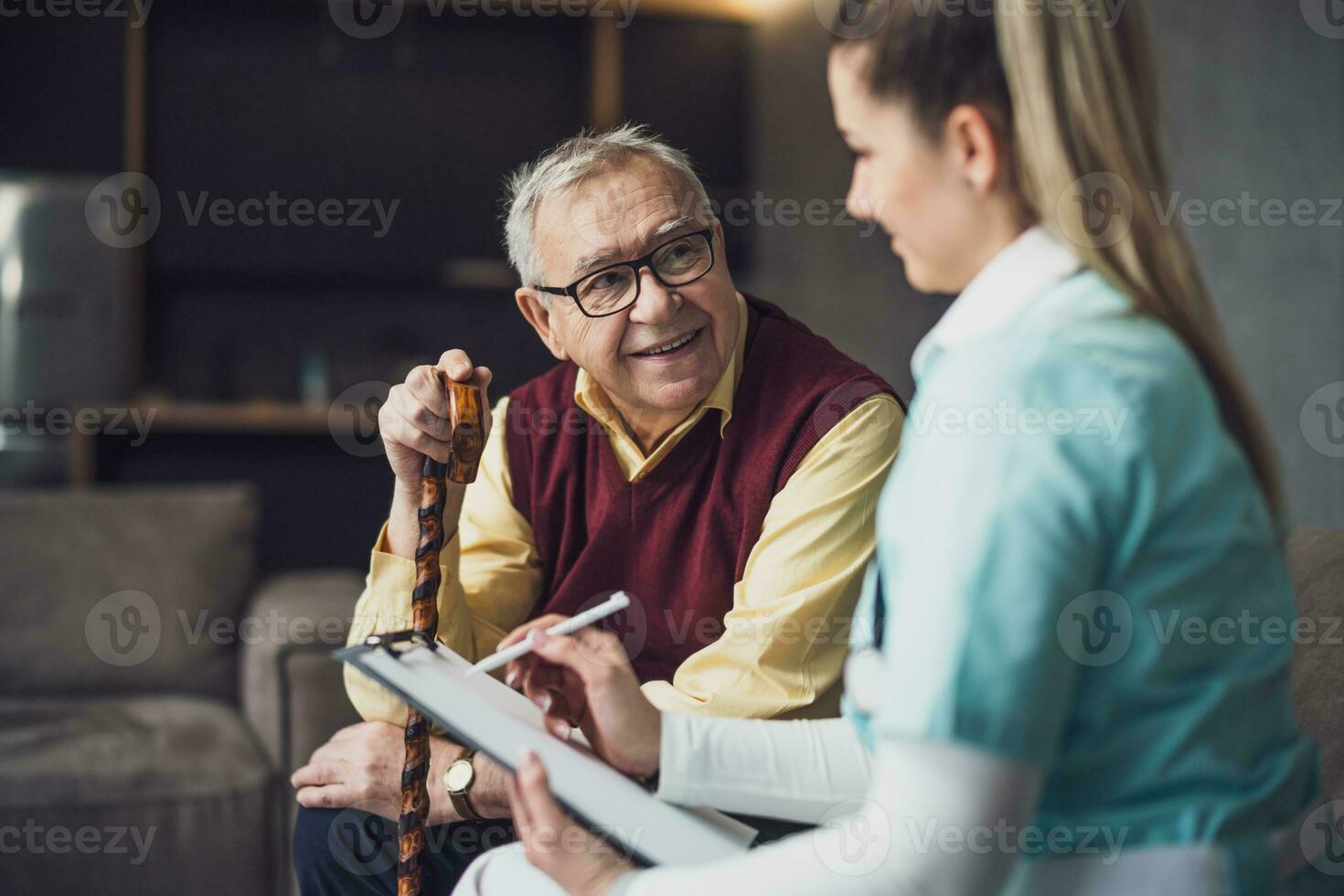 Elderly man with female caretaker at home. Health concept. photo